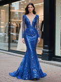 Woman wearing a blue sequin evening gown standing on a street.