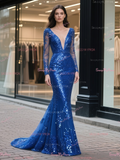 Woman wearing a blue sequin evening gown standing on a street.