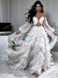 Model holding out the sheer puff sleeves and voluminous skirt of a white two-piece tulle ruffle prom dress displaying skirt movement.