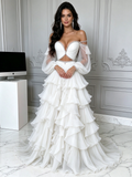 Front view of an ethereal white two-piece off-the-shoulder prom dress featuring a boned sweetheart bustier top, crystal trim, sheer tulle puff sleeves, and a tiered ruffle ball gown skirt.